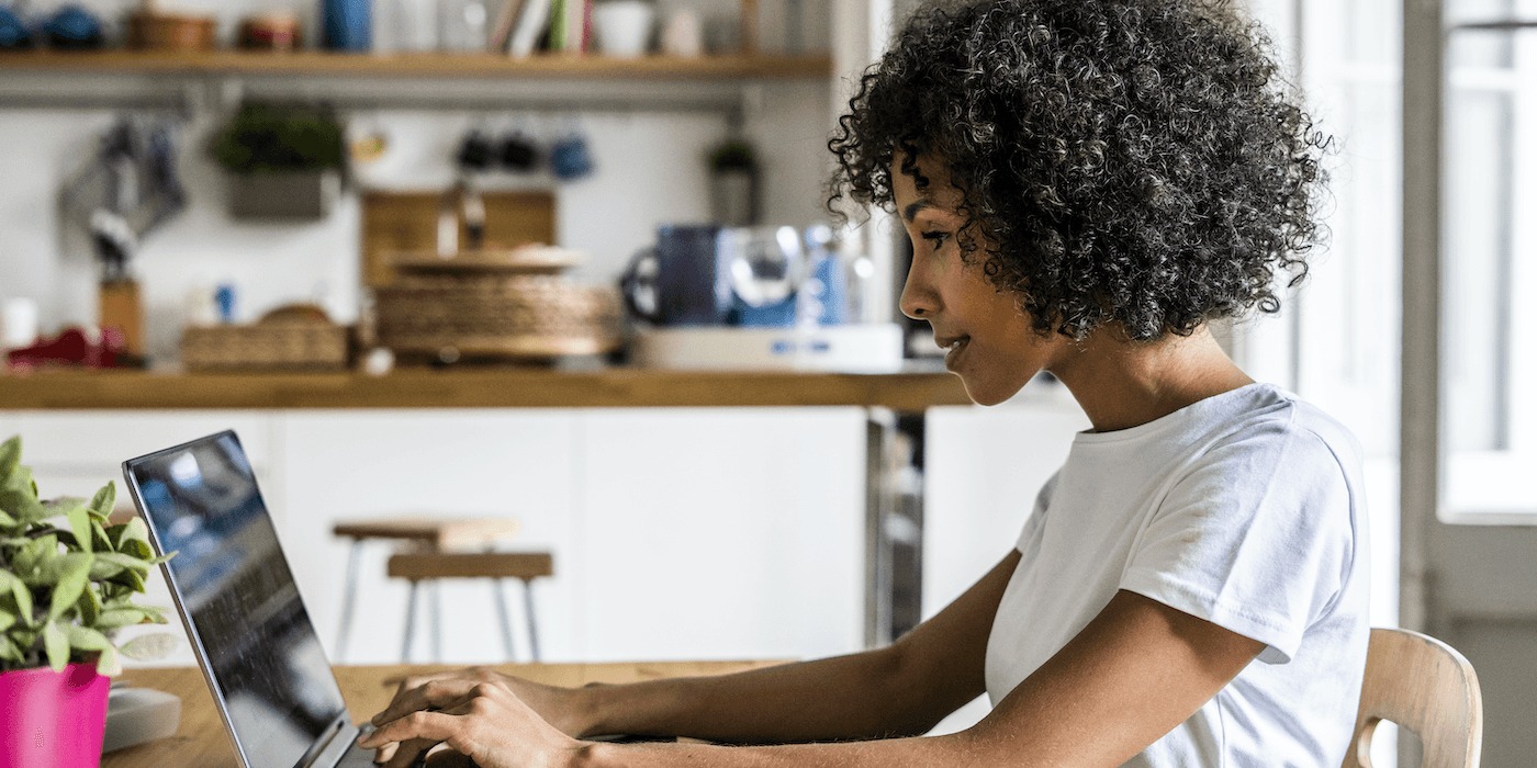 person sitting at a table at home typing on a laptop