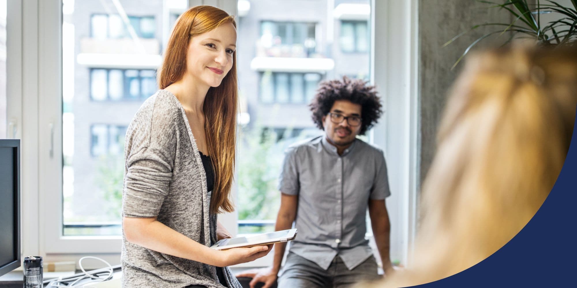 group of people talking in an office while sitting on desks