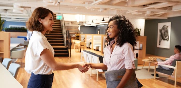 two people shaking hands in an open office